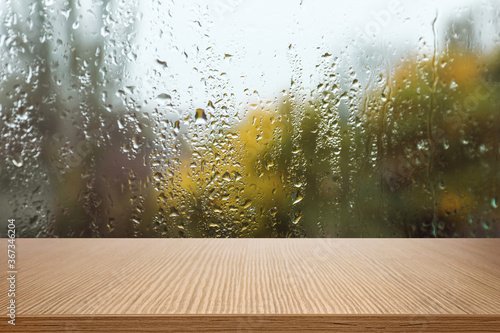 Wooden table near window on rainy day photo