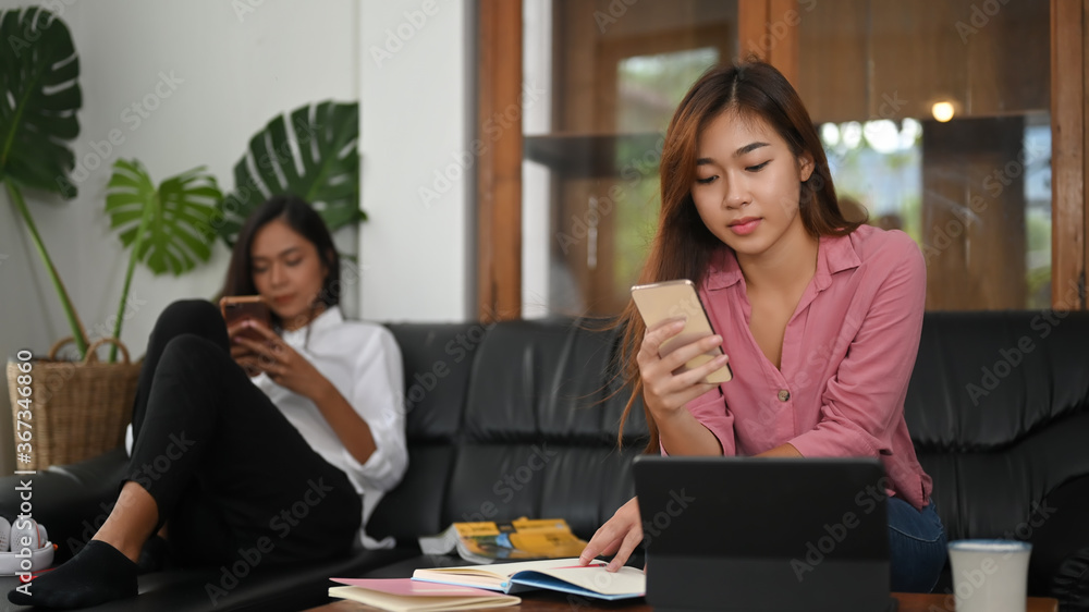 Women are using a smartphone and sitting together on the sofa. Women are using a smartphone and sitting together on the sofa.