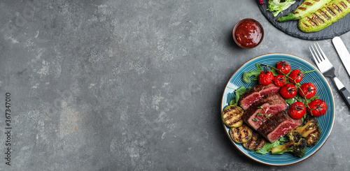 Flat lay composition with delicious sliced beef steak on grey table, space for text. Banner design
