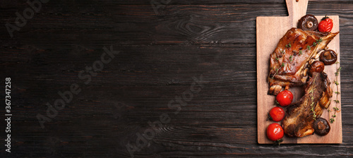 Serving board with delicious roasted ribs and space for text on wooden table, top view. Banner design
