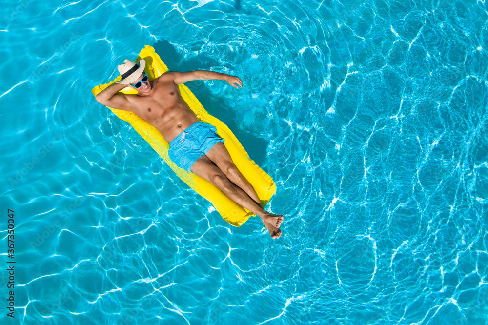Young man with inflatable mattress in swimming pool, top view. Space for text