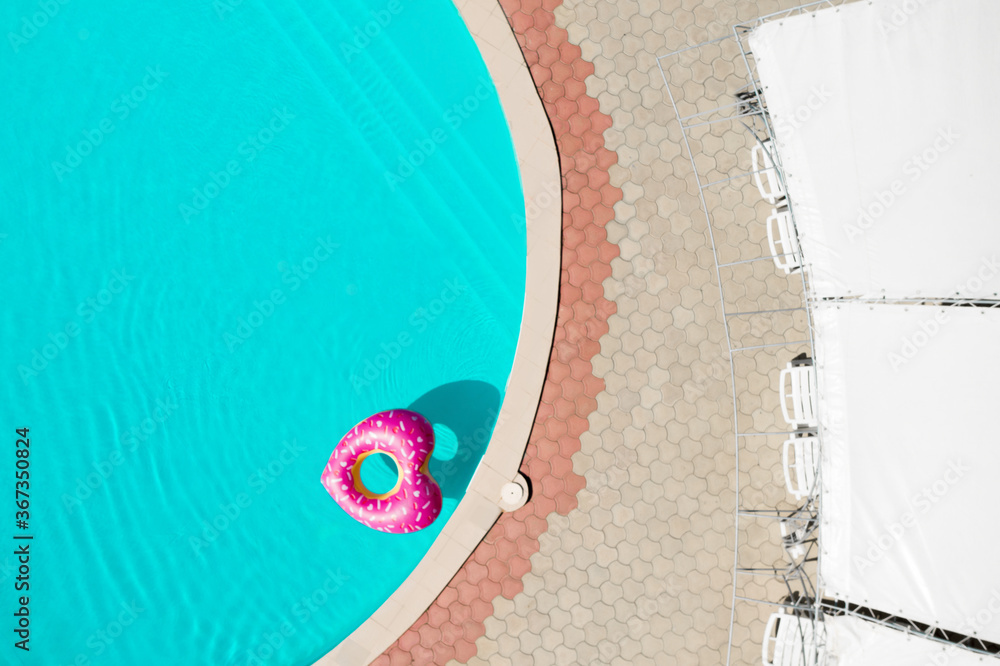 Heart shaped inflatable ring floating in swimming pool, top view. Summer vacation