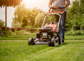Gardener mowing the lawn. Landscape design. Green grass background
