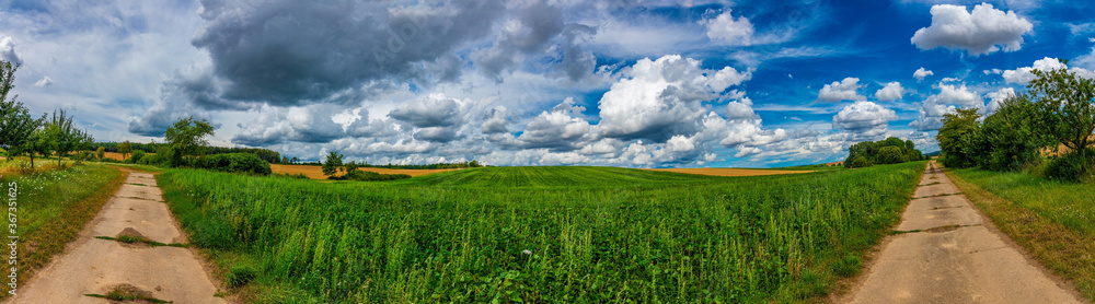 An ultra wide angle image of a green field, two roads on the sides and a blue sky with beautiful white clouds An ultra wide angle image of a green field, two roads on the sides and a blue sky with beautiful white clouds