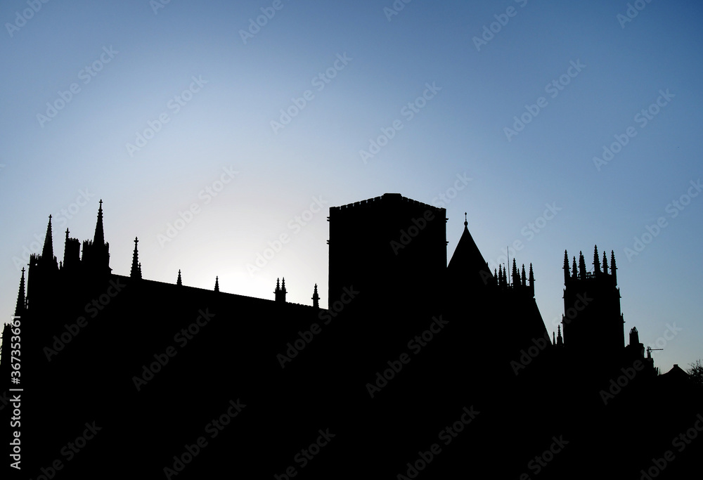 york minster in silhouette back lit against a morning sunrise and blue sky