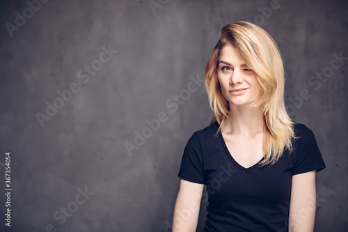 Winking young caucasian girl on dark background