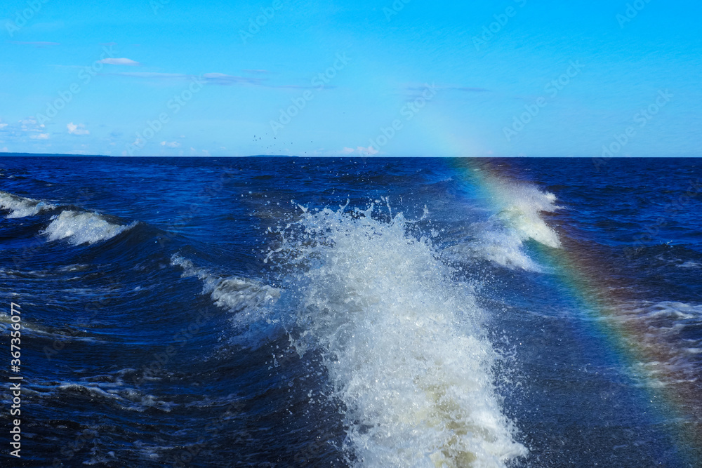Trail from a motor boat racing at high speed, water splash, rainbow Trail from a motor boat racing at high speed, water splash, rainbow