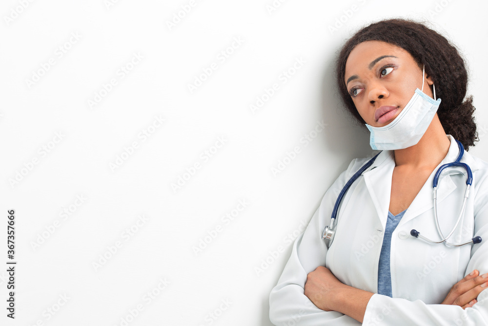 Portrait of a tired African American woman doctor. Sad nurse in a white coat and mask. Portrait of a tired African American woman doctor. Sad nurse in a white coat and mask.