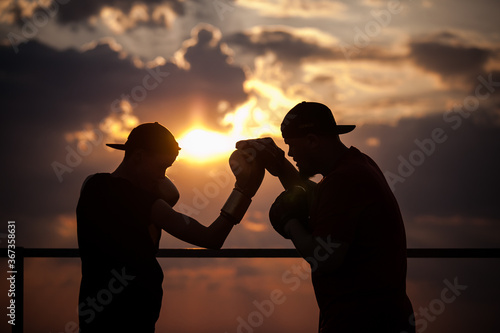 boxing sparring two men against the backdrop of a bright sunset on the roof