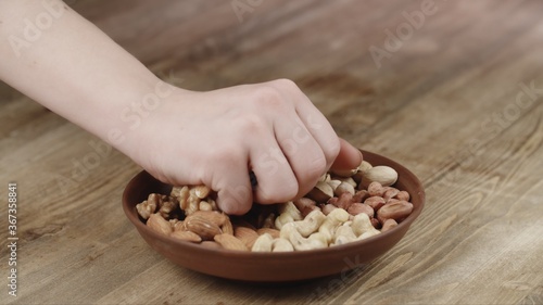 Woman Picks Up a handful of nuts, To Eat, From Her Bowl. took a nut on the left side