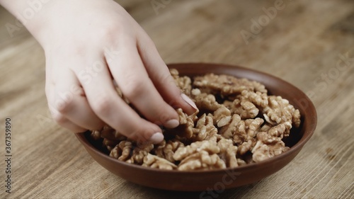 Woman Picks Up A Single walnut, To Eat, From Her Bowl. took a nut on the left side