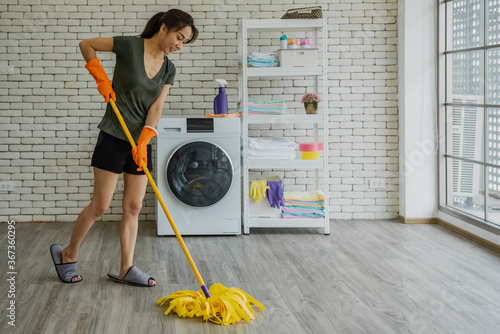 Canvas Print Young Asian woman cleaning floor with mop in laundry room.