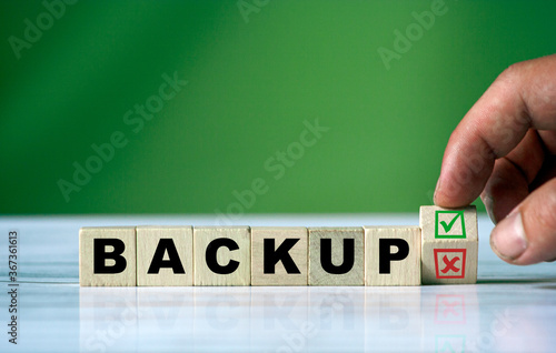 The hand turns the wooden cube and changes the word BACKUP