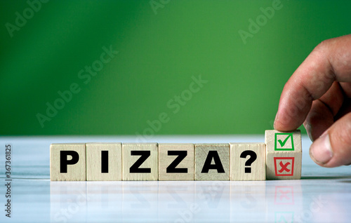 The hand turns the wooden cube and changes the word PIZZA
