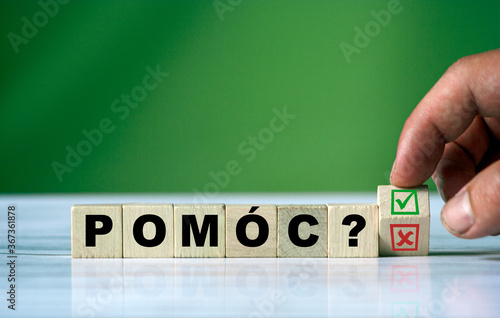 hand turns the wooden cube and changes the polish word POMÓC (english HELP)