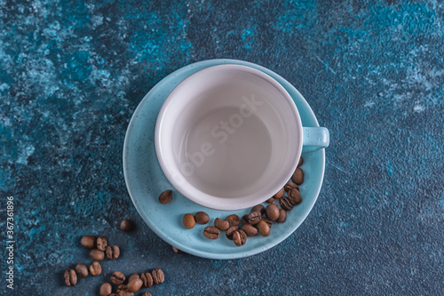 Empty blue cup for coffee and coffee beans on blue background,flat lay.
