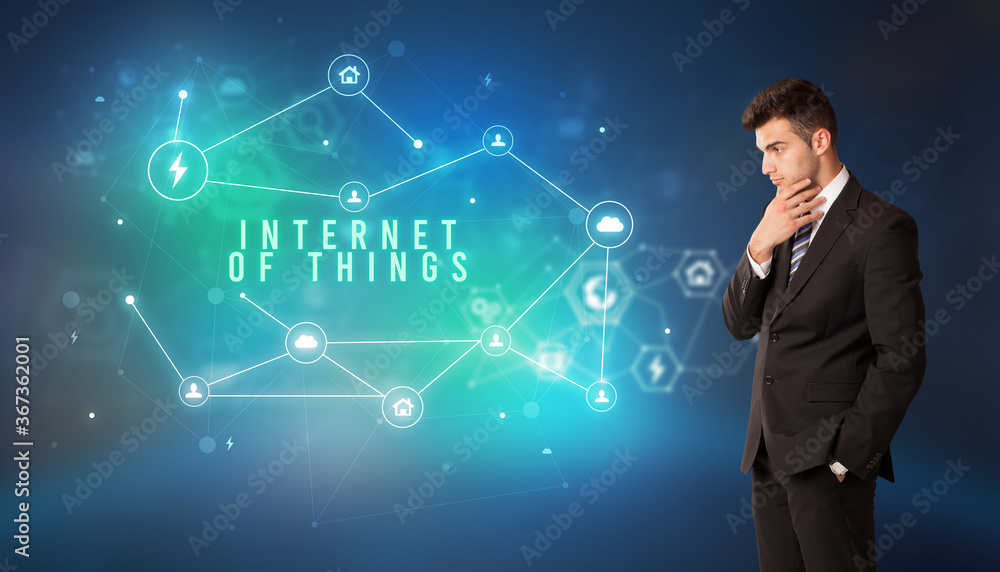 Businessman in front of cloud service icons with INTERNET OF THINGS inscription, modern technology concept Businessman in front of cloud service icons with INTERNET OF THINGS inscription, modern technology concept