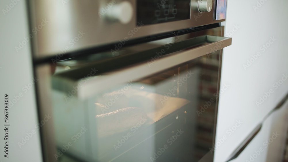 A female putting bread to the oven. A female putting bread to the oven.