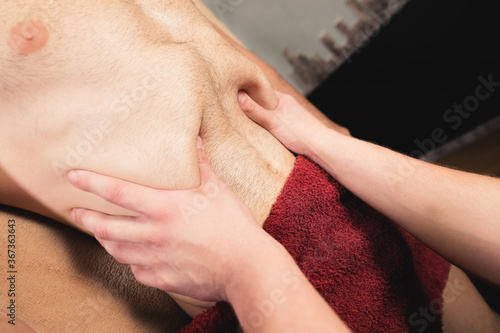 Close-up professional massage of the diaphragm to a man in a professional massage room. The concept of internal organs and abdominal cavity