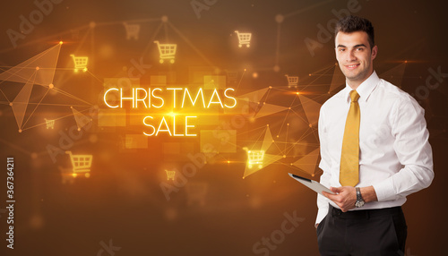 Businessman with shopping cart icons and CHRISTMAS SALE inscription, online shopping concept