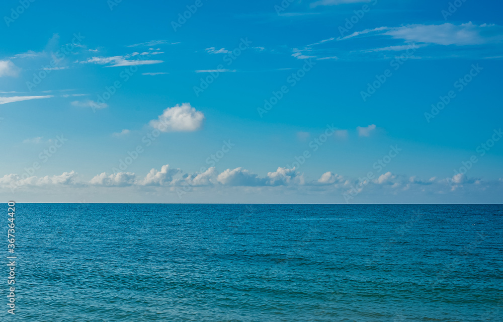 Obraz premium Blue sea surface extending to the horizon under a cloudy sky.