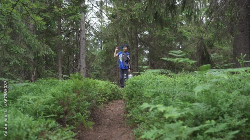Teenager boy carrying an aluminium milk can with blue berries In coniferous forest. Summertime In the woods. Teenager boy carrying an aluminium milk can with blue berries In coniferous forest. Summertime In the woods.