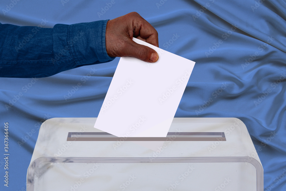 African American male hand lower ballot paper in transparent ballot box on background, concept of state elections, referendum African American male hand lower ballot paper in transparent ballot box on background, concept of state elections, referendum