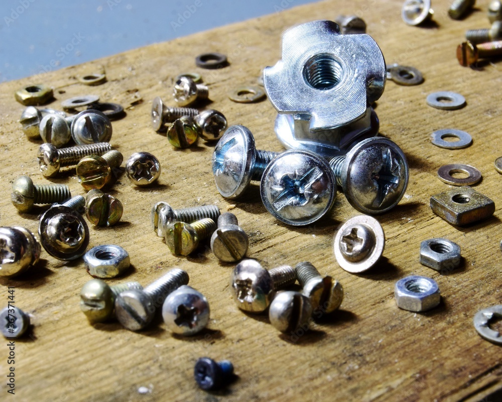 shiny silver bolts and nuts on a wooden background, selective close-up focus shiny silver bolts and nuts on a wooden background, selective close-up focus