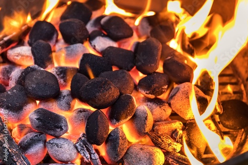 Top View Of Hot Flaming Charcoal Briquettes Glowing In The BBQ Grill Pit. Grill briquettes that are burning and waiting to be glowed for grilling. photo