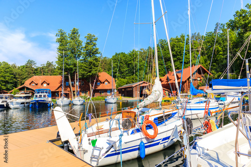 Sailing boats on lake shore in Ruciane-Nida "Pod Debem" town marina in early ...