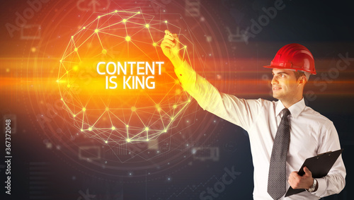 Handsome businessman with helmet drawing CONTENT IS KING inscription, social construction concept