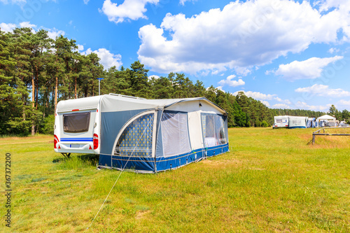 Trailers with tents on camping ground at lake Nidzkie shore on beautiful sunny summer day, Mazury Lake District, Poland