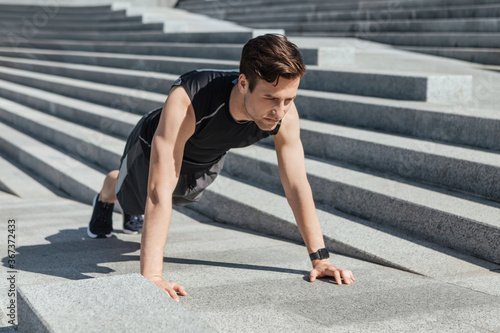 Active leisure and motivation. Guy with fitness tracker push up the city stairs