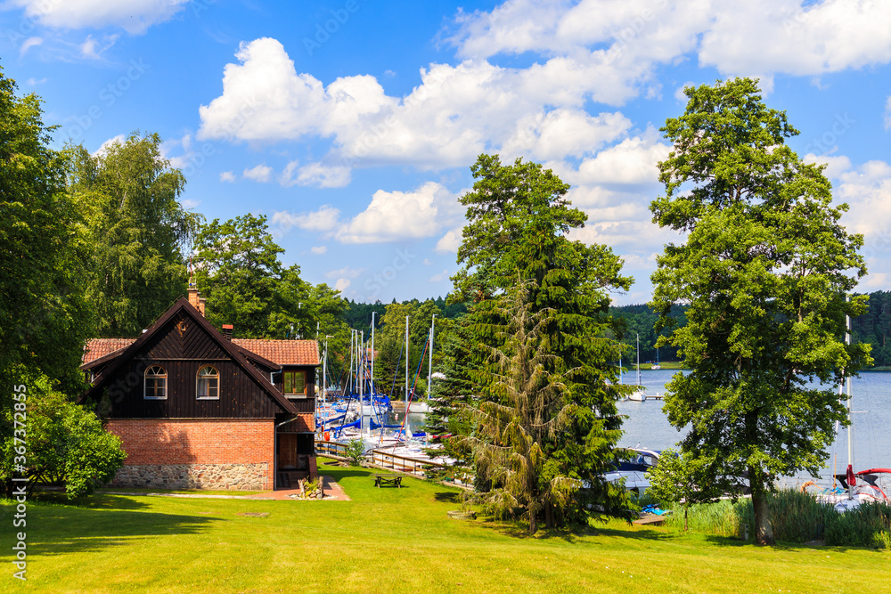 View of Wierzba port buildings with sailing boats on lake Beldany on summer sunny day, Mazury Lake District, Poland