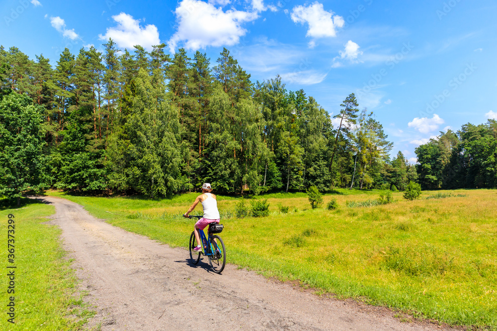 Young woman cycling on bike on forest road near Mikolajki town, Masurian Lakes, Poland Young woman cycling on bike on forest road near Mikolajki town, Masurian Lakes, Poland