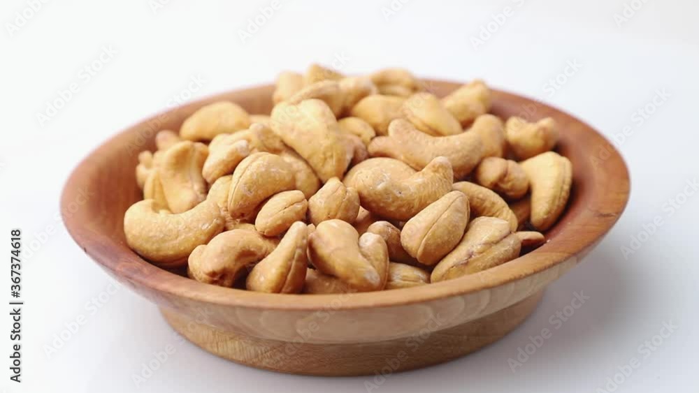 Rotating of cashew in wooden plate on white background. Side view, close up. Rotating of cashew in wooden plate on white background. Side view, close up.
