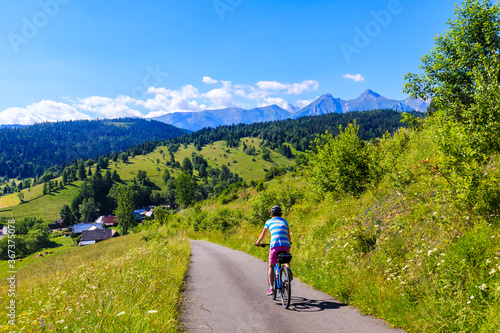 Young female biker cycling from Lapszanka Pass to Osturnia village in Tatra Mountains on beautiful summer sunny day, Slovakia