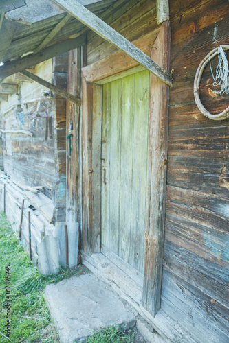 An old abandoned wooden building in a village manor. A structure made of cracked, sun-burned logs. photo