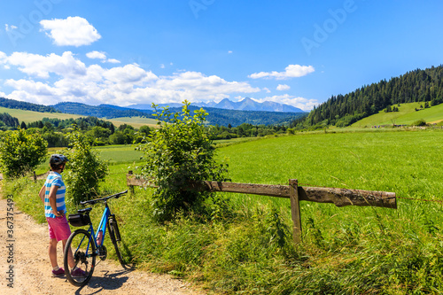 Young female biker looking at Tatra Mountains on beautiful summer sunny day near Kacwin village on Poland Slovakia border