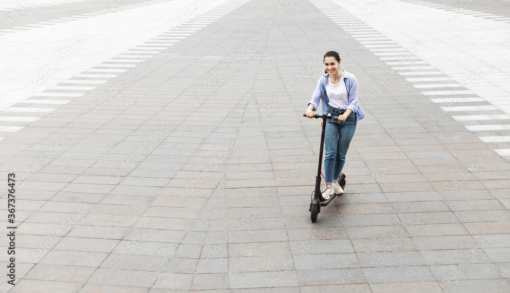 Happy girl having pleasant ride on electric kick scooter Happy girl having pleasant ride on electric kick scooter