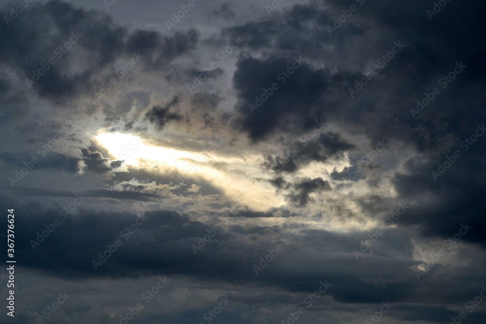 Dark stormy clouds and a sunbeam appearing. Dark stormy clouds and a sunbeam appearing.