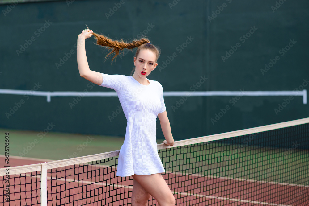 Sensual woman with tennis racket at net on lawn. Activity, energy, power. Sport, training, workout. Wellness, health.