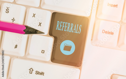 Text sign showing Referrals. Business photo showcasing act, action, or an instance of referring to someone for work Different colored keyboard key with accessories arranged on empty copy space photo