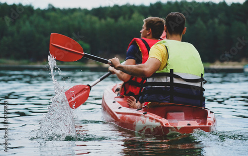 two guys in a red kayak on the river, in life jackets