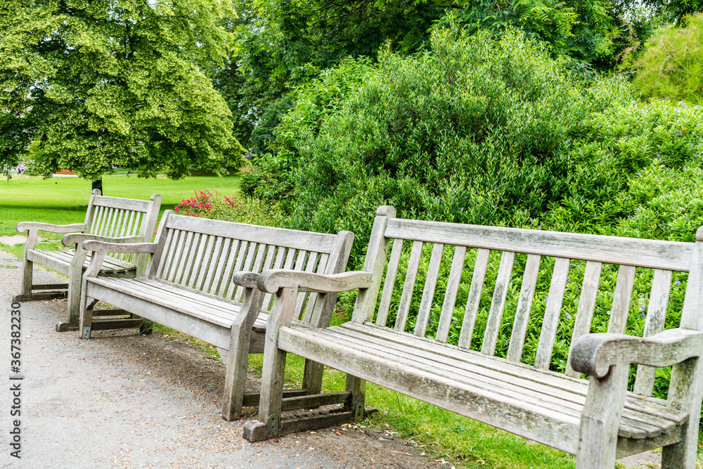 Three wooden park benches in a row, London, landscape orientation. Three wooden park benches in a row, London, landscape orientation.