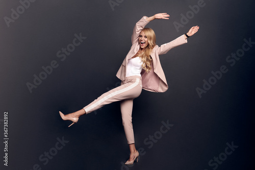 Full body photo of crazy business lady, raise leg, fists up unbelievable achievement cool wear office blazer pants suit shoes isolated on grey color background