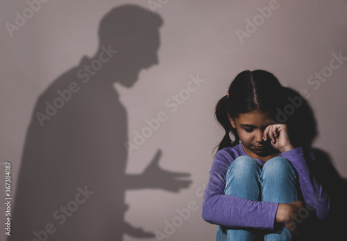 Child abuse. Father yelling at his daughter. Shadow of man on wall photo