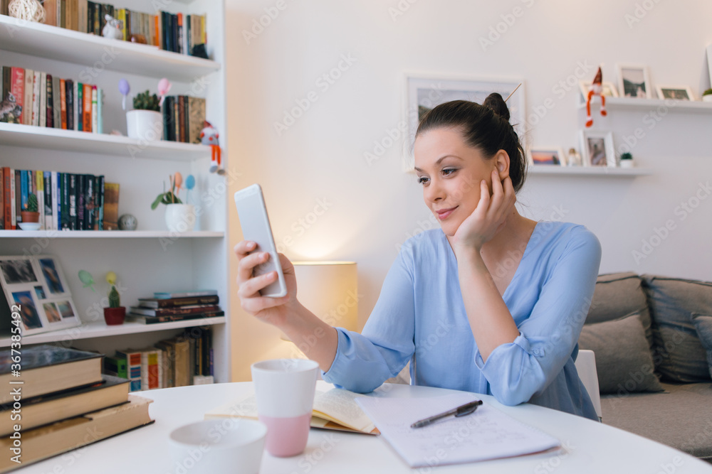 Young woman working at home and using mobile phone Young woman working at home and using mobile phone