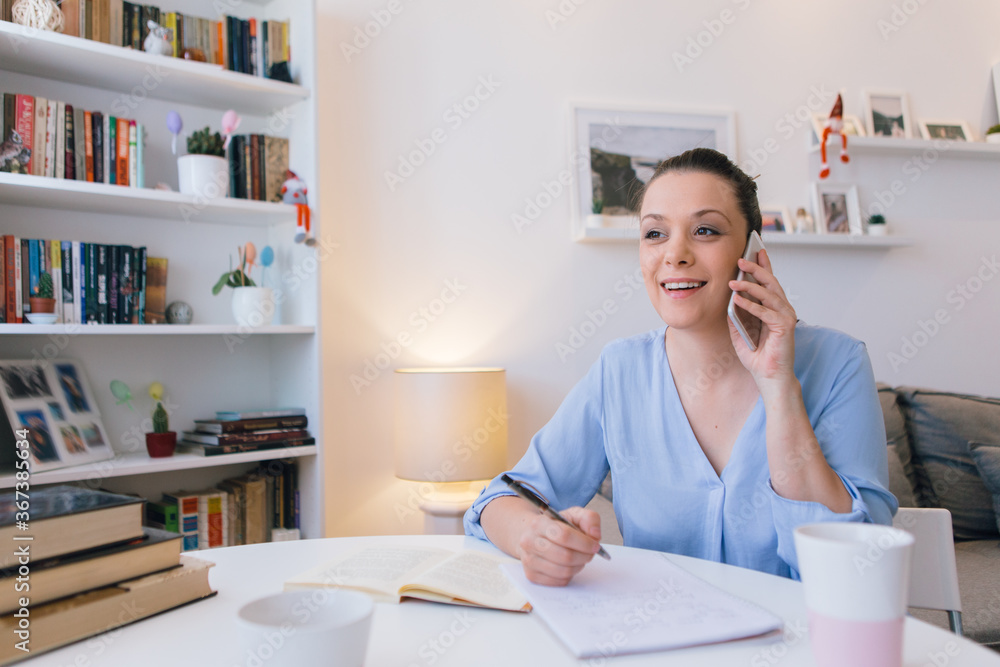 Young woman working at home and using mobile phone Young woman working at home and using mobile phone