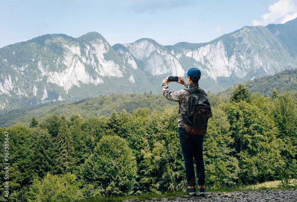 hiker with backpack taming photos in the mountains